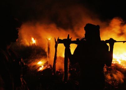 رجل مسلح يقف أمام نار مشتعلة في السودان