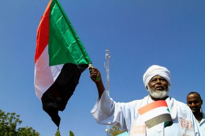 سوداني في الزي التقليدي يحمل علم السودان