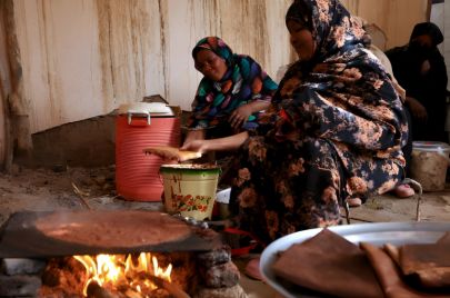 سيدات سودانيات يقمن بعواسة الآبري على الصاج والموقد المحلي الذي يشتعل بالحطب حسب العادات والتقاليد