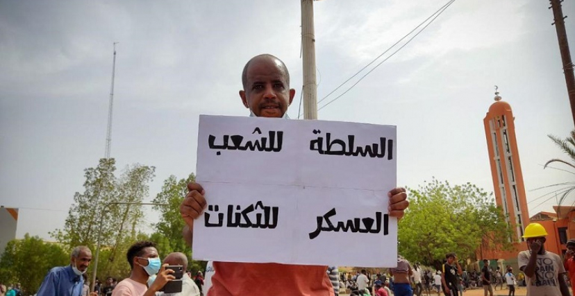 متظاهر يحمل لافتة مكتوب عليها "السلطة للشعب والعسكر للثكنات"