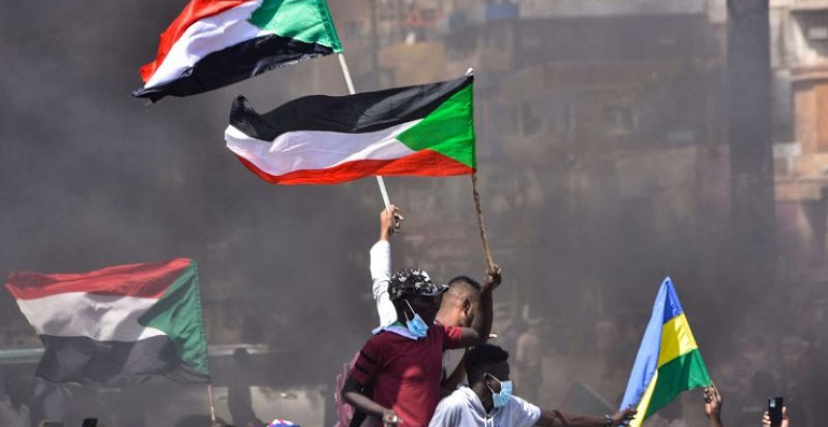 متظاهرون سودانيون يحملون أعلام السودان 